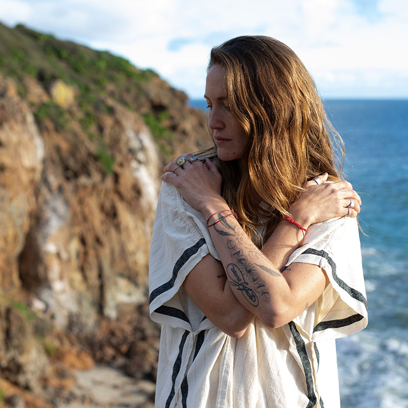 Embracing Change, Jacinta hugging herself in front of the beach